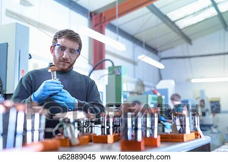 Stock Photography - Engineer working with electrodes for electrical discharge machine in precision engineering factory. Fotosearch
