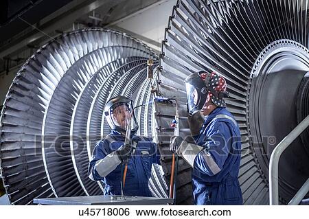 Stock Photograph - Engineers brazing ends of blades on low pressure steam turbine in turbine maintenance factory. Fotosearch