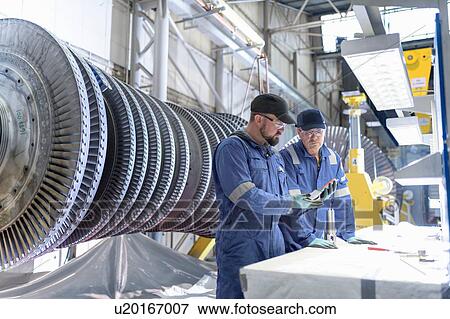 Stock Photo - Engineers inspecting turbine blade in turbine maintenance factory. Fotosearch