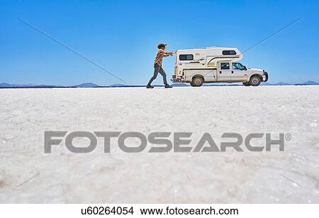False perspective image of boy on salt flats, pretending to push recreational vehicle, vehicle in background, Salar de Uyuni, Uyuni, Oruro, Bolivia, South America View Large Photo Image Picture - False perspective image of boy on salt flats, pretending to push recreational vehicle, vehicle in background, Salar de Uyuni, Uyuni, Oruro, Bolivia, South America. Fotosearch