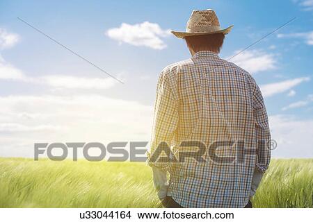 Picture - Farmer looking at the sun on the horizon.. Fotosearch
