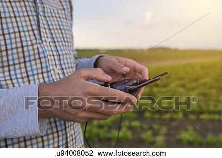 Stock Image - Farmer using drone remote controller.. Fotosearch