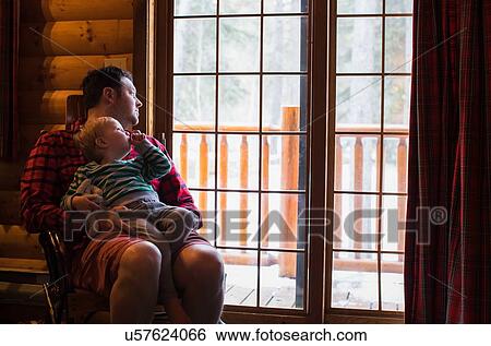 Stock Photograph - Father and son relaxing by window. Fotosearch