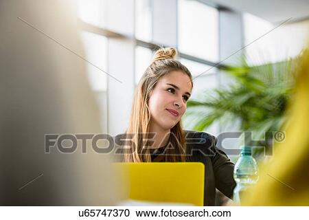 Stock Image - Female designer in meeting at design studio desk, over shoulder view. Fotosearch