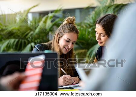 Picture - Female designers making notes at design studio desk, over shoulder view. Fotosearch
