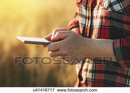 Female farmer standing in wheat field using mobile phone. View Large Photo Image Stock Photo - Female farmer standing in wheat field using mobile phone.. Fotosearch