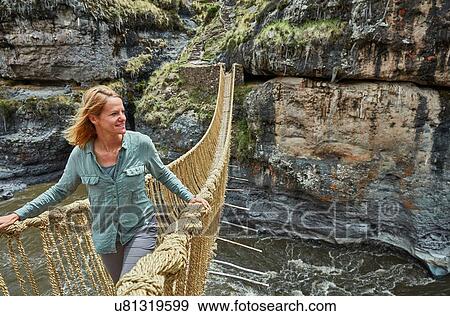 Stock Photo - Female tourist crossing Inca rope bridge, Huinchiri, Cusco, Peru. Fotosearch