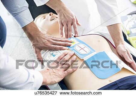 First-aider placing automated external defibrillator (AED) pads on a CPR training dummy. View Large Photo Image Stock Photo - First-aider placing automated external defibrillator (AED) pads on a CPR training dummy.. Fotosearch