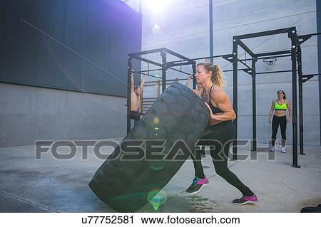 Four people exercising in gymnasium, woman in foreground lifting tire View Large Photo Image Stock Image - Four people exercising in gymnasium, woman in foreground lifting tire. Fotosearch