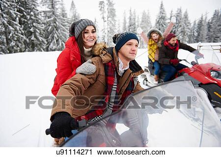 Stock Image - Friends riding snowmobiles in winter. Fotosearch