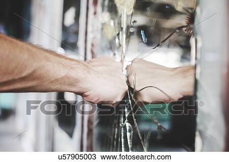 Stock Image - Frustrated and aggravated man punches a mirror.. Fotosearch