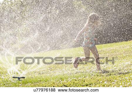 Girl (4-5) splashing in sprinkler water on lawn View Large Photo Image Stock Photo - Girl (4-5) splashing in sprinkler water on lawn. Fotosearch
