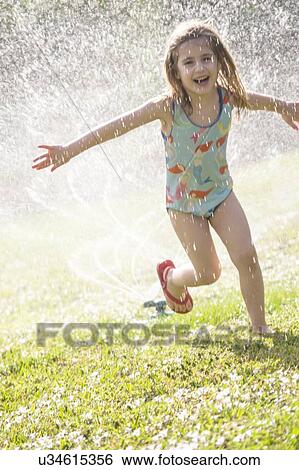 Girl (4-5) splashing in sprinkler water on lawn View Large Photo Image Stock Photograph - Girl (4-5) splashing in sprinkler water on lawn. Fotosearch
