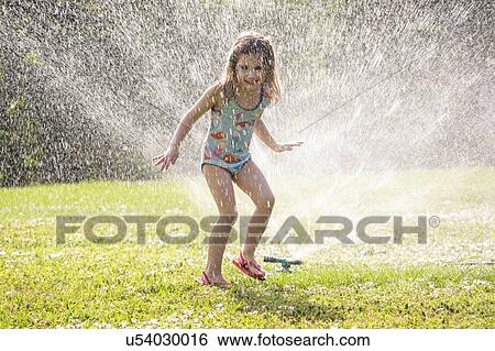 Girl (4-5) splashing in sprinkler water on lawn View Large Photo Image Stock Photograph - Girl (4-5) splashing in sprinkler water on lawn. Fotosearch