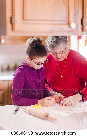 Girl and grandmother using cookie cutter on dough at kitchen counter View Large Photo Image Stock Photo - Girl and grandmother using cookie cutter on dough at kitchen counter. Fotosearch