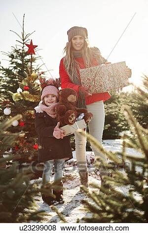 Girl and mother in christmas tree forest with christmas presents, portrait View Large Photo Image Stock Photo - Girl and mother in christmas tree forest with christmas presents, portrait. Fotosearch