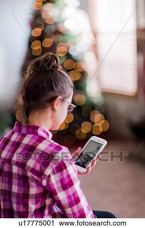 Stock Image - Girl at home, having video call with friend, using smartphone. Fotosearch