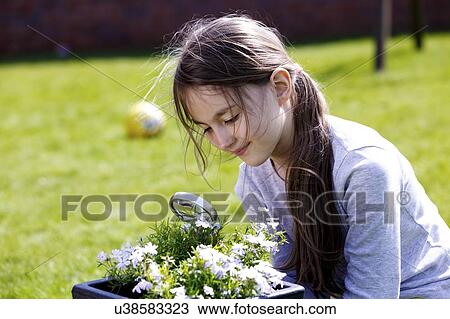 Stock Image - Girl examining a plant with a magnifying glass.. Fotosearch