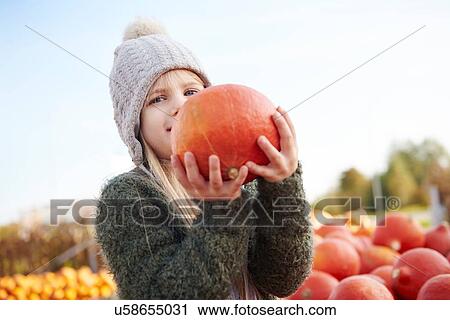 Girl holding harvested pumpkin in field View Large Photo Image Stock Image - Girl holding harvested pumpkin in field. Fotosearch