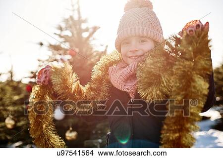 Girl in christmas tree forest wearing tinsel, portrait View Large Photo Image Picture - Girl in christmas tree forest wearing tinsel, portrait. Fotosearch