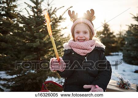 Stock Photography - Girl in christmas tree forest wearing antlers, portrait. Fotosearch