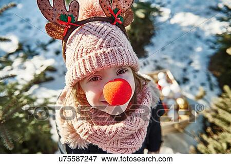 Stock Photo - Girl in christmas tree forest with red nose, high angle portrait. Fotosearch