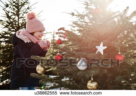 Girl looking at baubles on forest christmas tree View Large Photo Image Stock Photography - Girl looking at baubles on forest christmas tree. Fotosearch