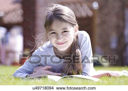 Girl lying on grass reading. View Large Photo Image Picture - Girl lying on grass reading.. Fotosearch