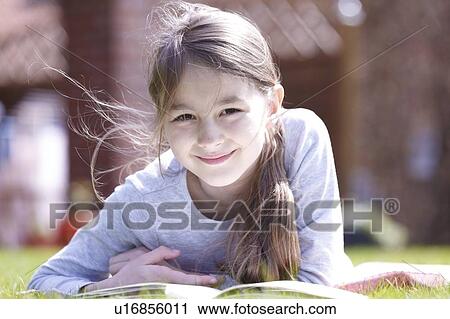 Girl lying on grass reading. View Large Photo Image Stock Image - Girl lying on grass reading.. Fotosearch