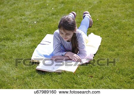 Girl lying on grass reading. View Large Photo Image Stock Image - Girl lying on grass reading.. Fotosearch