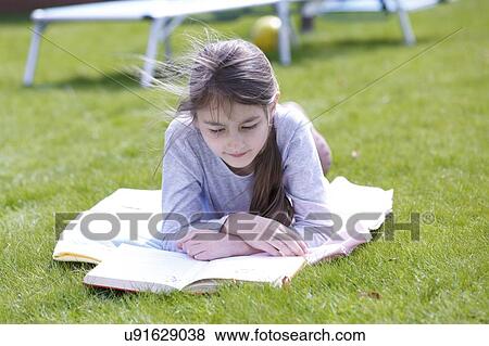 Stock Photo - Girl lying on grass reading.. Fotosearch