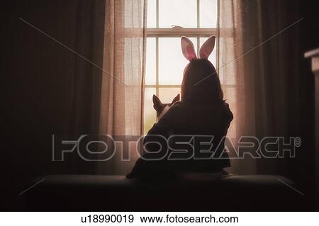 Stock Photo - Girl, sitting with dog, in front of window, rear view. Fotosearch