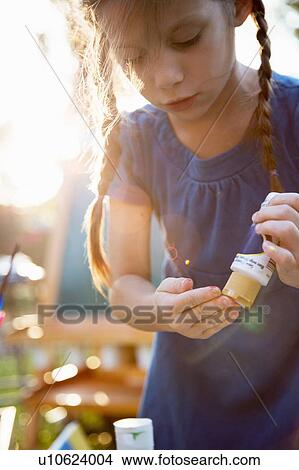 Girl squeezing finger paint onto fingers in garden View Large Photo Image Picture - Girl squeezing finger paint onto fingers in garden. Fotosearch
