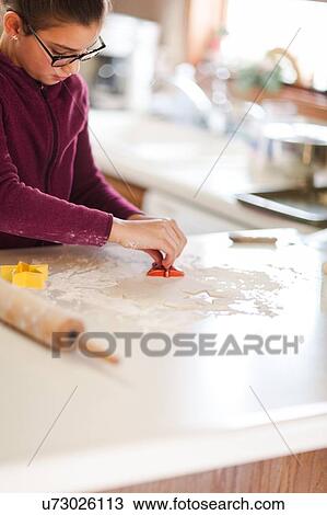 Girl using cookie cutter on dough at kitchen counter View Large Photo Image Stock Image - Girl using cookie cutter on dough at kitchen counter. Fotosearch