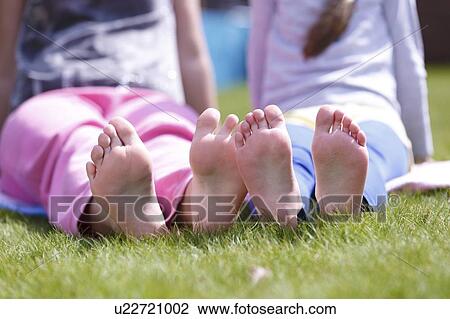 Stock Image - Girls' bare feet on grass.. Fotosearch