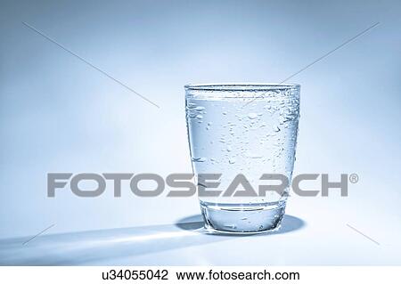Glass of water with condensation on a blue background. View Large Photo Image Stock Image - Glass of water with condensation on a blue background.. Fotosearch