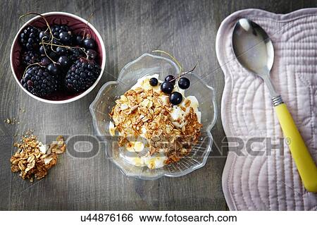Stock Photograph - Greek yoghurt with honey and muesli and bowl of berries, overhead view. Fotosearch