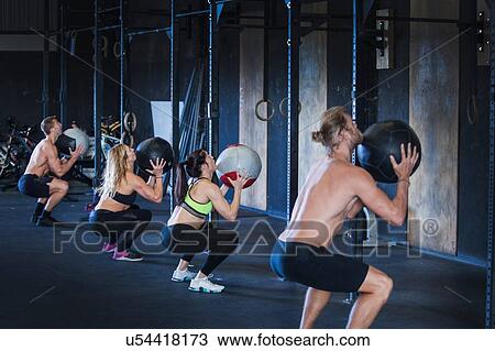 Group of people exercising in gym, using medicine balls View Large Photo Image Stock Image - Group of people exercising in gym, using medicine balls. Fotosearch