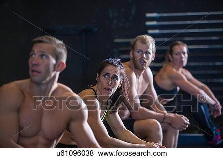 Stock Photo - Group of people exercising in gymnasium, catching break after using rowing machines. Fotosearch