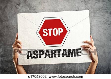 Stock Image - Hands holding banner with STOP ASPARTAME message, conceptual image.. Fotosearch