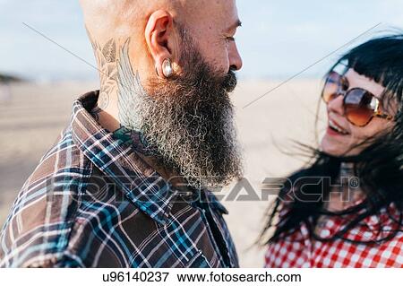 Stock Photo - Happy hipster couple face to face on beach, Valencia, Spain. Fotosearch
