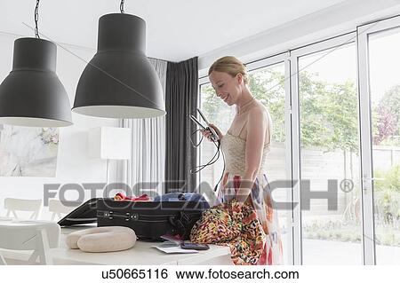 Happy mature woman packing suitcase for vacations View Large Photo Image Stock Photograph - Happy mature woman packing suitcase for vacations. Fotosearch