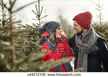 Stock Photo - Happy young couple in christmas tree forest. Fotosearch