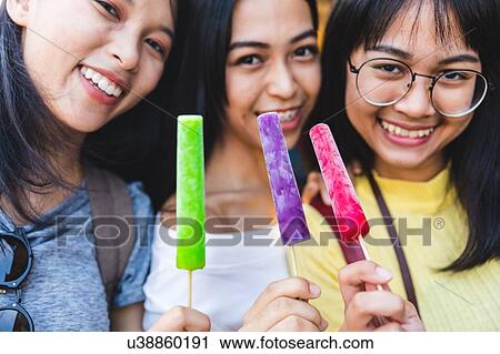 Stock Image - Happy young women with ice lollies. Fotosearch