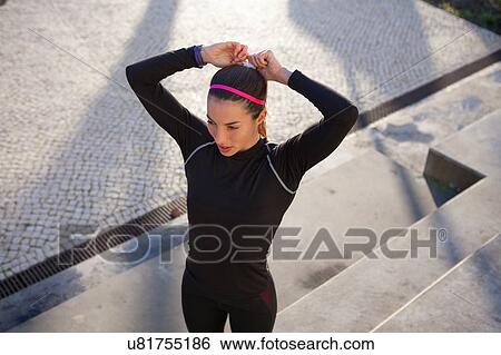 High angle view of young woman tying hair in ponytail View Large Photo Image Stock Photograph - High angle view of young woman tying hair in ponytail. Fotosearch