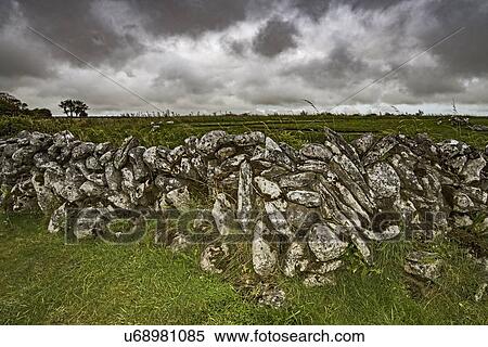 Stock Photography - Ireland, County Clare, Burren, Stone wall against stormy sky. Fotosearch