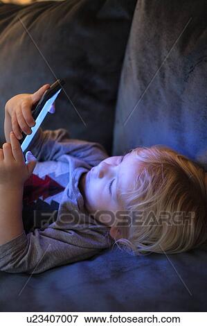 Little boy (2-3) lying down and playing game on smart phone View Large Photo Image Stock Photo - Little boy (2-3) lying down and playing game on smart phone. Fotosearch