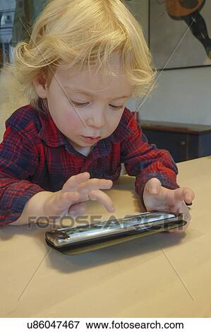 Stock Photo - Little boy (2-3) playing game on smart phone. Fotosearch