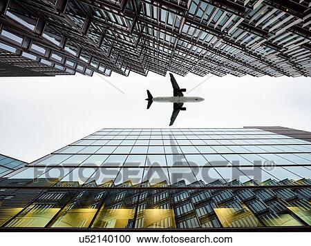 Low angle view of airplane flying between modern buildings, London City Airport, London, UK View Large Photo Image Stock Image - Low angle view of airplane flying between modern buildings, London City Airport, London, UK. Fotosearch
