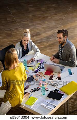 Picture - Male and female designers discussing colour swatches on design studio table. Fotosearch